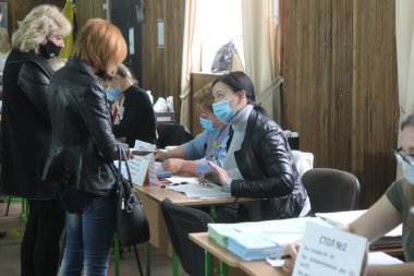ODESSA, UKRAINE -25.10.2020 - Ukrayna 'da seçimler. COVID-19 Coronavirus salgını sırasında yerel meclis üyelerinin seçim platformu. Oy pusulalarıyla maske ve eldiven takan insanlar