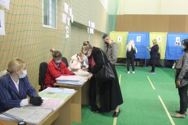ODESSA, UKRAINE -25.10.2020 - Ukrayna 'da seçimler. COVID-19 Coronavirus salgını sırasında yerel meclis üyelerinin seçim platformu. Oy pusulalarıyla maske ve eldiven takan insanlar
