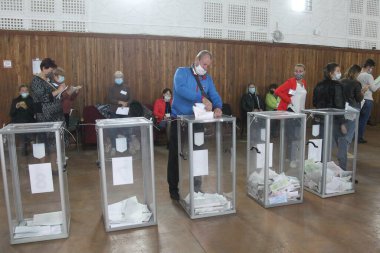 ODESSA, UKRAINE -25.10.2020 - Ukrayna 'da seçimler. COVID-19 Coronavirus salgını sırasında yerel meclis üyelerinin seçim platformu. Oy pusulalarıyla maske ve eldiven takan insanlar