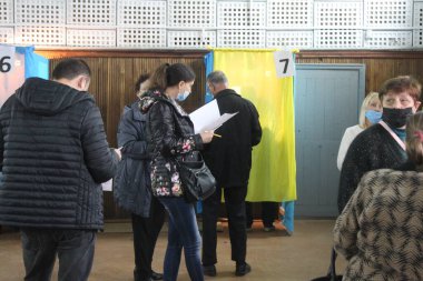 ODESSA, UKRAINE -25.10.2020 - Ukrayna 'da seçimler. COVID-19 Coronavirus salgını sırasında yerel meclis üyelerinin seçim platformu. Oy pusulalarıyla maske ve eldiven takan insanlar