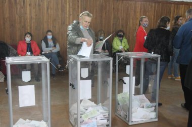 ODESSA, UKRAINE -25.10.2020 - Ukrayna 'da seçimler. COVID-19 Coronavirus salgını sırasında yerel meclis üyelerinin seçim platformu. Oy pusulalarıyla maske ve eldiven takan insanlar