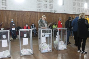 ODESSA, UKRAINE -25.10.2020 - Ukrayna 'da seçimler. COVID-19 Coronavirus salgını sırasında yerel meclis üyelerinin seçim platformu. Oy pusulalarıyla maske ve eldiven takan insanlar