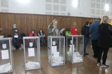 ODESSA, UKRAINE -25.10.2020 - Ukrayna 'da seçimler. COVID-19 Coronavirus salgını sırasında yerel meclis üyelerinin seçim platformu. Oy pusulalarıyla maske ve eldiven takan insanlar