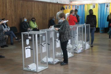 ODESSA, UKRAINE -25.10.2020 - Ukrayna 'da seçimler. COVID-19 Coronavirus salgını sırasında yerel meclis üyelerinin seçim platformu. Oy pusulalarıyla maske ve eldiven takan insanlar