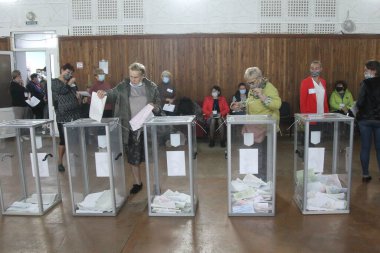 ODESSA, UKRAINE -25.10.2020 - Ukrayna 'da seçimler. COVID-19 Coronavirus salgını sırasında yerel meclis üyelerinin seçim platformu. Oy pusulalarıyla maske ve eldiven takan insanlar