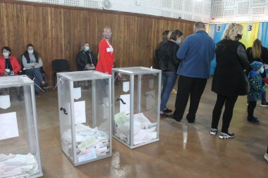 ODESSA, UKRAINE -25.10.2020 - Ukrayna 'da seçimler. COVID-19 Coronavirus salgını sırasında yerel meclis üyelerinin seçim platformu. Oy pusulalarıyla maske ve eldiven takan insanlar