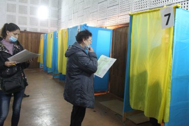 ODESSA, UKRAINE -25.10.2020 - Ukrayna 'da seçimler. COVID-19 Coronavirus salgını sırasında yerel meclis üyelerinin seçim platformu. Oy pusulalarıyla maske ve eldiven takan insanlar