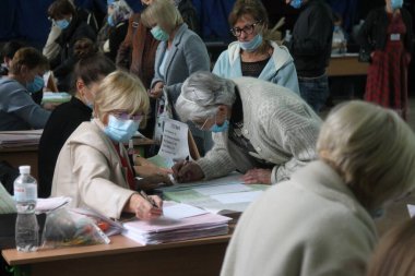 ODESSA, UKRAINE -25.10.2020 - Ukrayna 'da seçimler. COVID-19 Coronavirus salgını sırasında yerel meclis üyelerinin seçim platformu. Oy pusulalarıyla maske ve eldiven takan insanlar