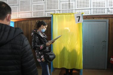 ODESSA, UKRAINE -25.10.2020 - Ukrayna 'da seçimler. COVID-19 Coronavirus salgını sırasında yerel meclis üyelerinin seçim platformu. Oy pusulalarıyla maske ve eldiven takan insanlar