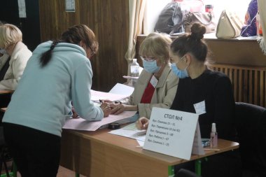 ODESSA, UKRAINE -25.10.2020 - Ukrayna 'da seçimler. COVID-19 Coronavirus salgını sırasında yerel meclis üyelerinin seçim platformu. Oy pusulalarıyla maske ve eldiven takan insanlar