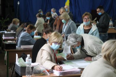 ODESSA, UKRAINE -25.10.2020 - Ukrayna 'da seçimler. COVID-19 Coronavirus salgını sırasında yerel meclis üyelerinin seçim platformu. Oy pusulalarıyla maske ve eldiven takan insanlar