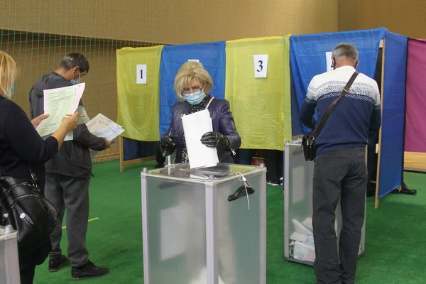 ODESSA, UKRAINE -25.10.2020 - Ukrayna 'da seçimler. COVID-19 Coronavirus salgını sırasında yerel meclis üyelerinin seçim platformu. Oy pusulalarıyla maske ve eldiven takan insanlar