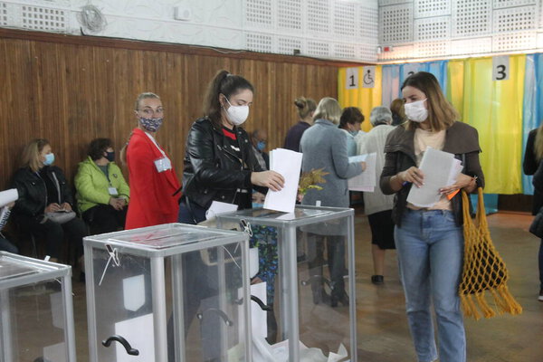 ОДЕССА, Украина -25.10.2020 - Выборы в Украине. Избирательная платформа для выборов местных советников во время пандемии коронавируса COVID-19. Люди в масках и перчатках с бюллетенями для голосования