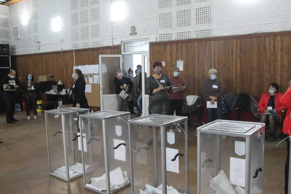 ODESSA, UKRAINE -25.10.2020 - Ukrayna 'da seçimler. COVID-19 Coronavirus salgını sırasında yerel meclis üyelerinin seçim platformu. Oy pusulalarıyla maske ve eldiven takan insanlar