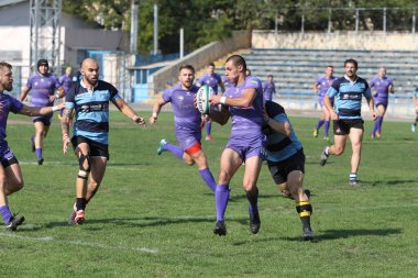 ODESSA, UKRAINE - 20.10.17 - Ukrain Rugby Şampiyonası POLYTECHNIK (Odessa) - siyah. Kamyanets Podolsky - mor. Rugby oyuncularının top için yoğun mücadelesi. Yeşil sahada dinamik bir oyun. Acımasız ragbi
