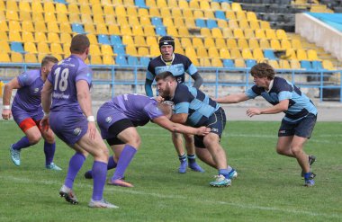 ODESSA, UKRAINE - 20.10.17 - Ukrain Rugby Şampiyonası POLYTECHNIK (Odessa) - siyah. Kamyanets Podolsky - mor. Rugby oyuncularının top için yoğun mücadelesi. Yeşil sahada dinamik bir oyun. Acımasız ragbi