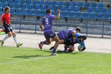 ODESSA, UKRAINE - 20.10.17 - Ukrain Rugby Şampiyonası POLYTECHNIK (Odessa) - siyah. Kamyanets Podolsky - mor. Rugby oyuncularının top için yoğun mücadelesi. Yeşil sahada dinamik bir oyun. Acımasız ragbi
