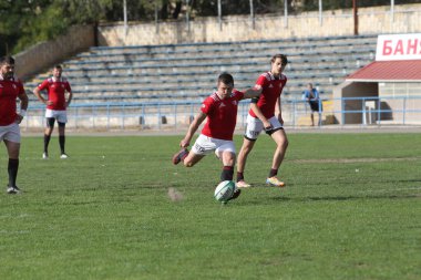 ODESSA, UKRAINE -20.10.17 - Ukrayna ragbi şampiyonası finali CREDO (Odessa) - kırmızı, OLYMPIK (Kharkiv) siyah rugby oyuncularının top için yoğun mücadelesi. Yeşil sahada dinamik bir oyun. Acımasız ragbi
