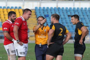 ODESSA, UKRAINE -20.10.17 - Ukrayna ragbi şampiyonası finali CREDO (Odessa) - kırmızı, OLYMPIK (Kharkiv) siyah rugby oyuncularının top için yoğun mücadelesi. Yeşil sahada dinamik bir oyun. Acımasız ragbi