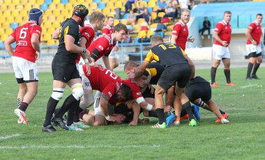 ODESSA, UKRAINE -20.10.17 - Ukrayna ragbi şampiyonası finali CREDO (Odessa) - kırmızı, OLYMPIK (Kharkiv) siyah rugby oyuncularının top için yoğun mücadelesi. Yeşil sahada dinamik bir oyun. Acımasız ragbi