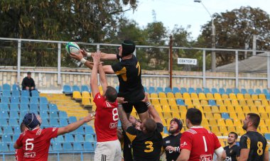 ODESSA, UKRAINE -20.10.17 - Ukrayna ragbi şampiyonası finali CREDO (Odessa) - kırmızı, OLYMPIK (Kharkiv) siyah rugby oyuncularının top için yoğun mücadelesi. Yeşil sahada dinamik bir oyun. Acımasız ragbi