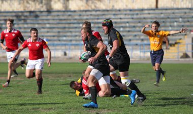 ODESSA, UKRAINE -20.10.17 - Ukrayna ragbi şampiyonası finali CREDO (Odessa) - kırmızı, OLYMPIK (Kharkiv) siyah rugby oyuncularının top için yoğun mücadelesi. Yeşil sahada dinamik bir oyun. Acımasız ragbi