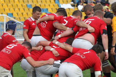 ODESSA, UKRAINE -20.10.17 - Ukrayna ragbi şampiyonası finali CREDO (Odessa) - kırmızı, OLYMPIK (Kharkiv) siyah rugby oyuncularının top için yoğun mücadelesi. Yeşil sahada dinamik bir oyun. Acımasız ragbi