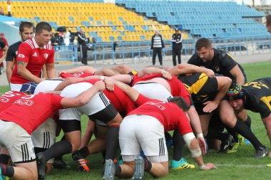 ODESSA, UKRAINE -20.10.17 - Ukrayna ragbi şampiyonası finali CREDO (Odessa) - kırmızı, OLYMPIK (Kharkiv) siyah rugby oyuncularının top için yoğun mücadelesi. Yeşil sahada dinamik bir oyun. Acımasız ragbi
