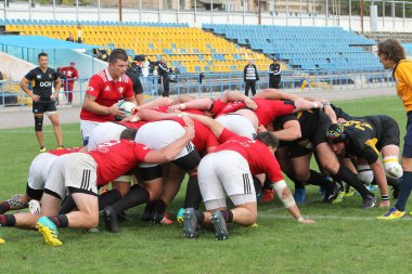 ODESSA, UKRAINE -20.10.17 - Ukrayna ragbi şampiyonası finali CREDO (Odessa) - kırmızı, OLYMPIK (Kharkiv) siyah rugby oyuncularının top için yoğun mücadelesi. Yeşil sahada dinamik bir oyun. Acımasız ragbi