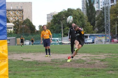 ODESSA, UKRAINE -20.10.17 - Ukrayna ragbi şampiyonası finali CREDO (Odessa) - kırmızı, OLYMPIK (Kharkiv) siyah rugby oyuncularının top için yoğun mücadelesi. Yeşil sahada dinamik bir oyun. Acımasız ragbi