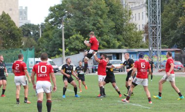 ODESSA, UKRAINE -20.10.17 - Ukrayna ragbi şampiyonası finali CREDO (Odessa) - kırmızı, OLYMPIK (Kharkiv) siyah rugby oyuncularının top için yoğun mücadelesi. Yeşil sahada dinamik bir oyun. Acımasız ragbi