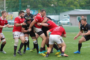 ODESSA, UKRAINE -20.10.17 - Ukrayna ragbi şampiyonası finali CREDO (Odessa) - kırmızı, OLYMPIK (Kharkiv) siyah rugby oyuncularının top için yoğun mücadelesi. Yeşil sahada dinamik bir oyun. Acımasız ragbi