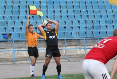 ODESSA, UKRAINE -20.10.17 - Ukrayna ragbi şampiyonası finali CREDO (Odessa) - kırmızı, OLYMPIK (Kharkiv) siyah rugby oyuncularının top için yoğun mücadelesi. Yeşil sahada dinamik bir oyun. Acımasız ragbi