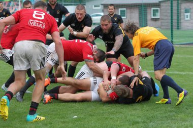 ODESSA, UKRAINE -20.10.17 - Ukrayna ragbi şampiyonası finali CREDO (Odessa) - kırmızı, OLYMPIK (Kharkiv) siyah rugby oyuncularının top için yoğun mücadelesi. Yeşil sahada dinamik bir oyun. Acımasız ragbi