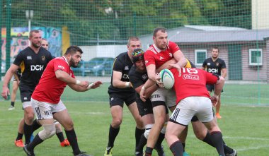 ODESSA, UKRAINE -20.10.17 - Ukrayna ragbi şampiyonası finali CREDO (Odessa) - kırmızı, OLYMPIK (Kharkiv) siyah rugby oyuncularının top için yoğun mücadelesi. Yeşil sahada dinamik bir oyun. Acımasız ragbi