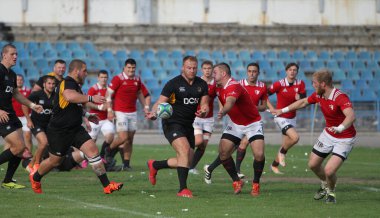 ODESSA, UKRAINE -20.10.17 - Ukrayna ragbi şampiyonası finali CREDO (Odessa) - kırmızı, OLYMPIK (Kharkiv) siyah rugby oyuncularının top için yoğun mücadelesi. Yeşil sahada dinamik bir oyun. Acımasız ragbi