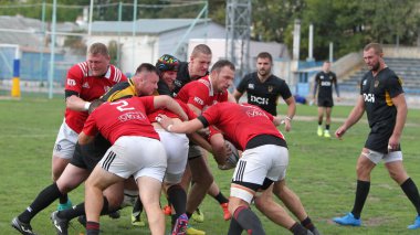 ODESSA, UKRAINE -20.10.17 - Ukrayna ragbi şampiyonası finali CREDO (Odessa) - kırmızı, OLYMPIK (Kharkiv) siyah rugby oyuncularının top için yoğun mücadelesi. Yeşil sahada dinamik bir oyun. Acımasız ragbi