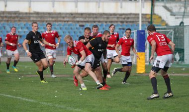 ODESSA, UKRAINE -20.10.17 - Ukrayna ragbi şampiyonası finali CREDO (Odessa) - kırmızı, OLYMPIK (Kharkiv) siyah rugby oyuncularının top için yoğun mücadelesi. Yeşil sahada dinamik bir oyun. Acımasız ragbi