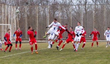 ODESSA, Ukrayna 02.24.2021 - FC Chernomorets (beyaz) Odessa yerel FC Real Pharma kulübüyle şehir şampiyonasında bir araya geldi. Futbolcular futbol stadyumunun çimlerinde topla hareket halindeler