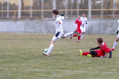 ODESSA, Ukrayna 02.24.2021 - FC Chernomorets (beyaz) Odessa yerel FC Real Pharma kulübüyle şehir şampiyonasında bir araya geldi. Futbolcular futbol stadyumunun çimlerinde topla hareket halindeler
