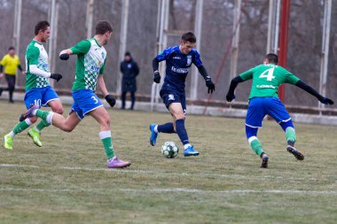 ODESSA, Ukrayna 02.24.2021 - FC Chernomorets (mavi) Odessa, FC Kristall Kherson ile dostluk maçı yaptı. Futbolcular bir futbol stadyumunun çimlerinde topla hareket halindeler.