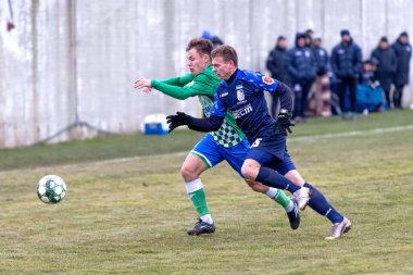 ODESSA, Ukrayna 02.24.2021 - FC Chernomorets (mavi) Odessa, FC Kristall Kherson ile dostluk maçı yaptı. Futbolcular bir futbol stadyumunun çimlerinde topla hareket halindeler.