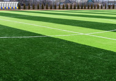 Profesyonel bir futbol sahasında yapay yeşil çimenler. Açık hava suni futbol sahası oyuncuların çıkışını bekliyor