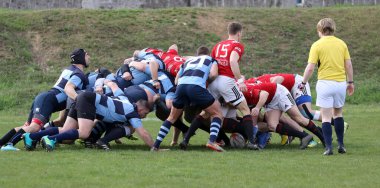 ODESSA, UKRAINE - 17 Nisan 2021: Rugby Kupası 7. Odessa Polytechnic Derby - mavi, CREDO - kırmızı. Erkeklerin ragbi maçının gergin anı. Dramatik ve zorlu erkek ragbi müsabakası. Erkekler ragbi sahasında savaşır
