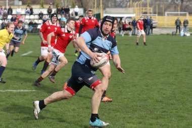 ODESSA, UKRAINE - 17 Nisan 2021: Rugby Kupası 7. Odessa Polytechnic Derby - mavi, CREDO - kırmızı. Erkeklerin ragbi maçının gergin anı. Dramatik ve zorlu erkek ragbi müsabakası. Erkekler ragbi sahasında savaşır