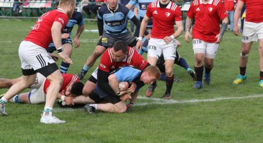ODESSA, UKRAINE - 17 Nisan 2021: Rugby Kupası 7. Odessa Polytechnic Derby - mavi, CREDO - kırmızı. Erkeklerin ragbi maçının gergin anı. Dramatik ve zorlu erkek ragbi müsabakası. Erkekler ragbi sahasında savaşır