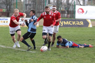 ODESSA, UKRAINE - 17 Nisan 2021: Rugby Kupası 7. Odessa Polytechnic Derby - mavi, CREDO - kırmızı. Erkeklerin ragbi maçının gergin anı. Dramatik ve zorlu erkek ragbi müsabakası. Erkekler ragbi sahasında savaşır