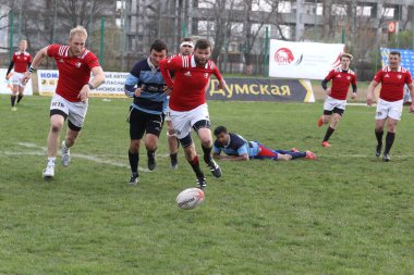 ODESSA, UKRAINE - 17 Nisan 2021: Rugby Kupası 7. Odessa Polytechnic Derby - mavi, CREDO - kırmızı. Erkeklerin ragbi maçının gergin anı. Dramatik ve zorlu erkek ragbi müsabakası. Erkekler ragbi sahasında savaşır