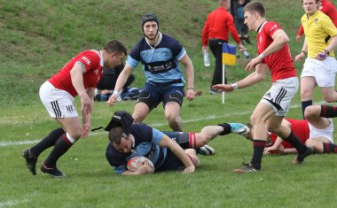 ODESSA, UKRAINE - 17 Nisan 2021: Rugby Kupası 7. Odessa Polytechnic Derby - mavi, CREDO - kırmızı. Erkeklerin ragbi maçının gergin anı. Dramatik ve zorlu erkek ragbi müsabakası. Erkekler ragbi sahasında savaşır