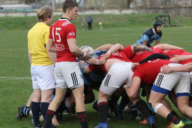 ODESSA, UKRAINE - 17 Nisan 2021: Rugby Kupası 7. Odessa Polytechnic Derby - mavi, CREDO - kırmızı. Erkeklerin ragbi maçının gergin anı. Dramatik ve zorlu erkek ragbi müsabakası. Erkekler ragbi sahasında savaşır